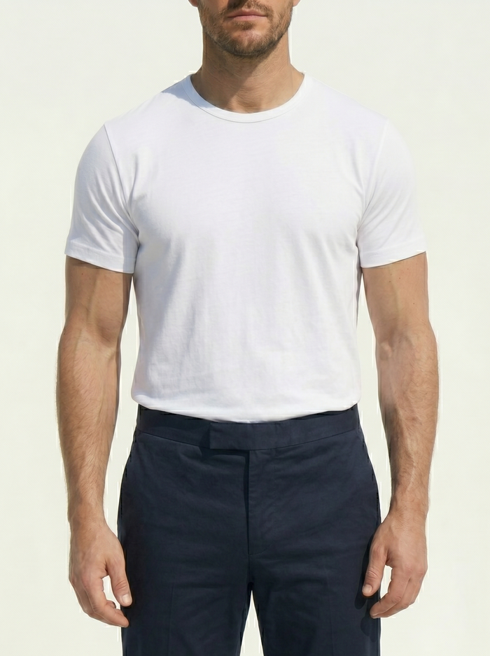 Man wearing a white t-shirt and navy pants on a plain background