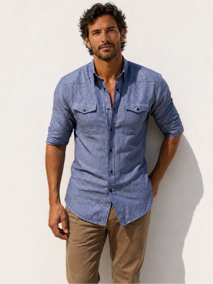 Man wearing a blue button-up shirt and beige pants against a white background