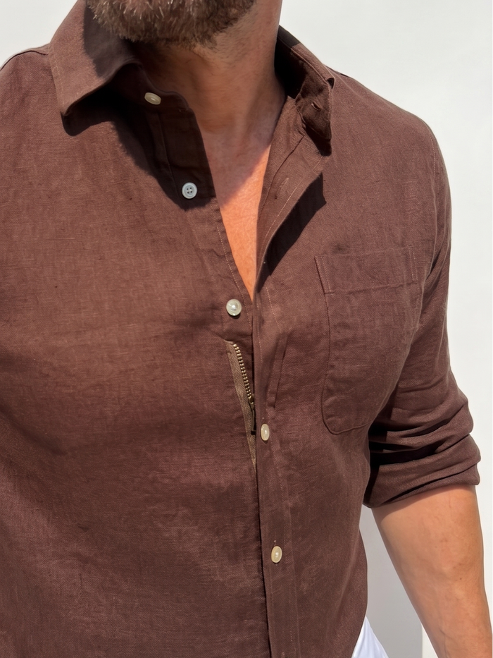 Man wearing a brown shirt with long sleeves against a white background