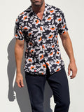 Man wearing a black floral patterned shirt against a white background