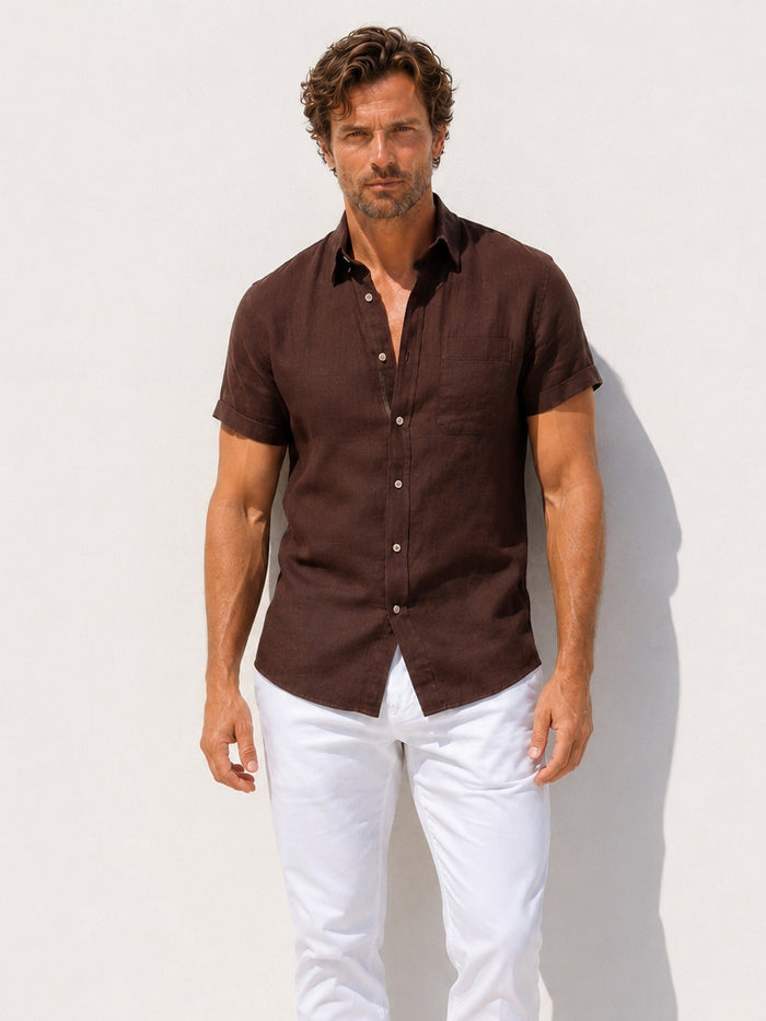 Man wearing a brown shirt and white pants against a light background