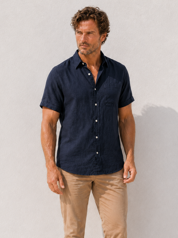 Man wearing a navy shirt and beige pants against a white background