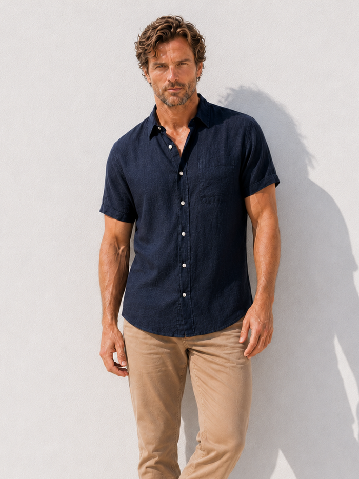 Man wearing a navy shirt and beige pants against a white background