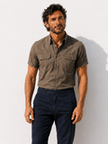 Man wearing a brown shirt and dark pants against a white background