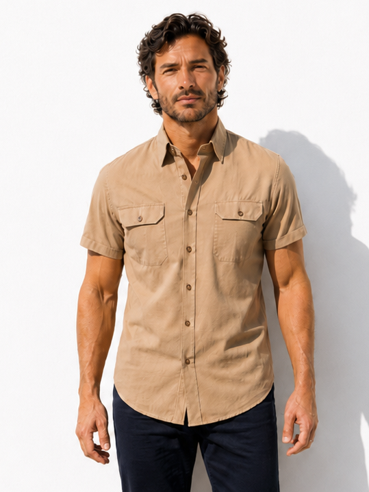 Man wearing a beige short-sleeve shirt and dark pants against a white background